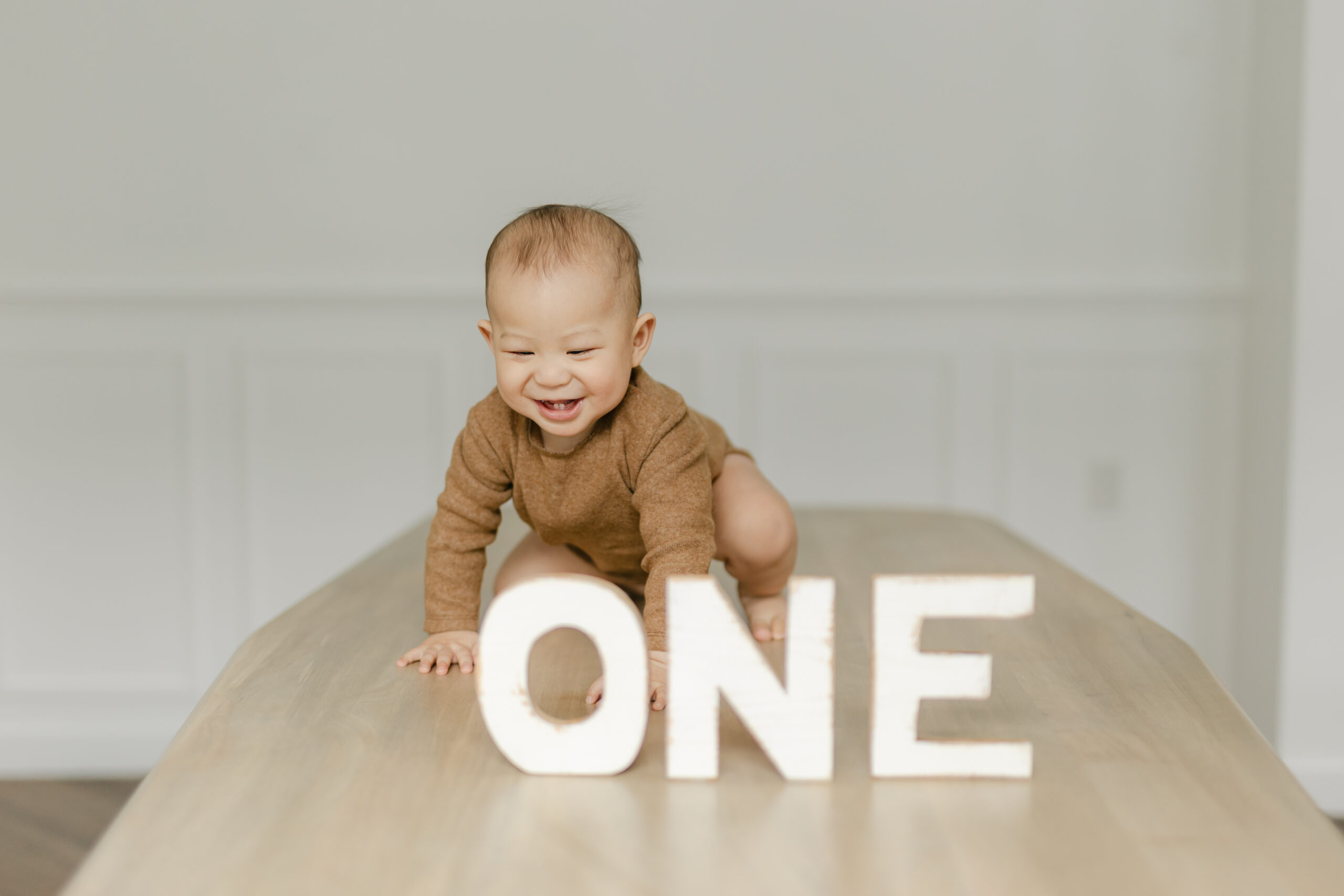 baby standing behind a one sign for his first birthday
