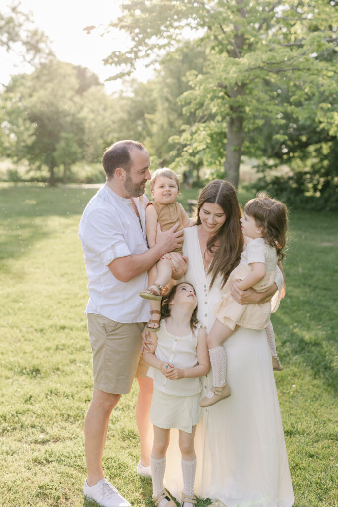 A family of 5 play in a grassy field at sunset during a Toronto Family Session