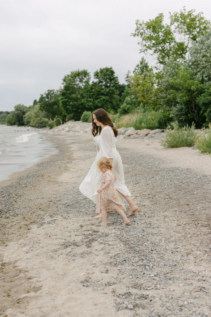 Mom and daughter are holding hands and walking on the beach