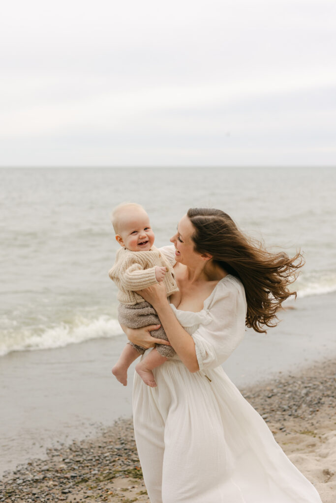 A mom is hugging her son at a Toronto beach and smiling at him