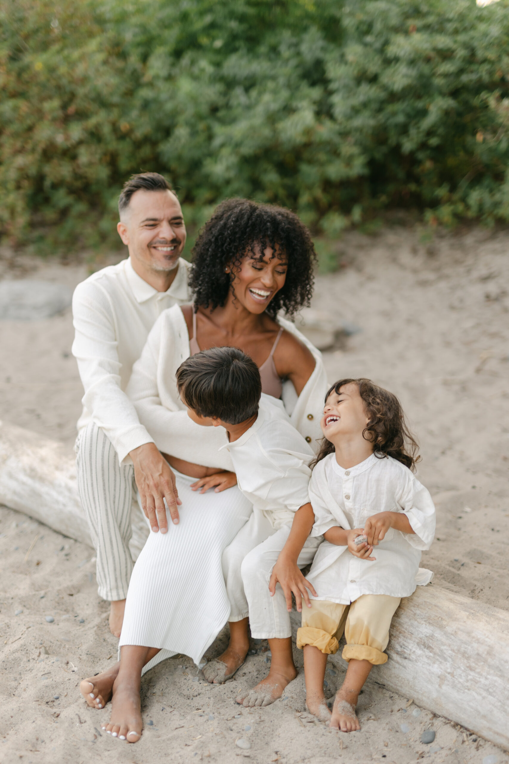 Family of 4 sitting at a Toronto beach and laughing