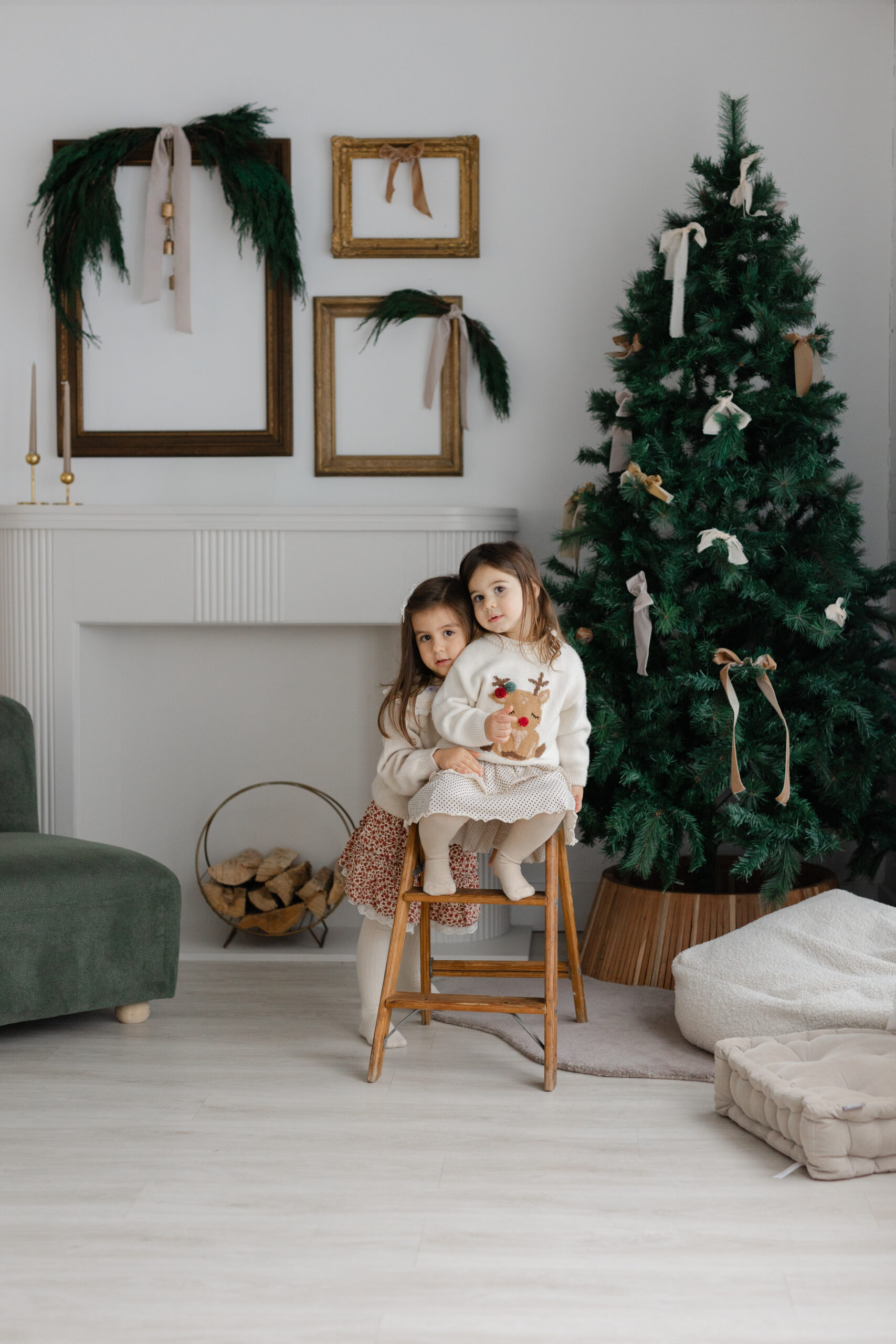 Two sisters posing by the Christmas tree in a studio in Toronto