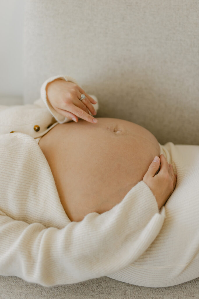 an expecting woman massaging her pregnant belly in a Toronto studio